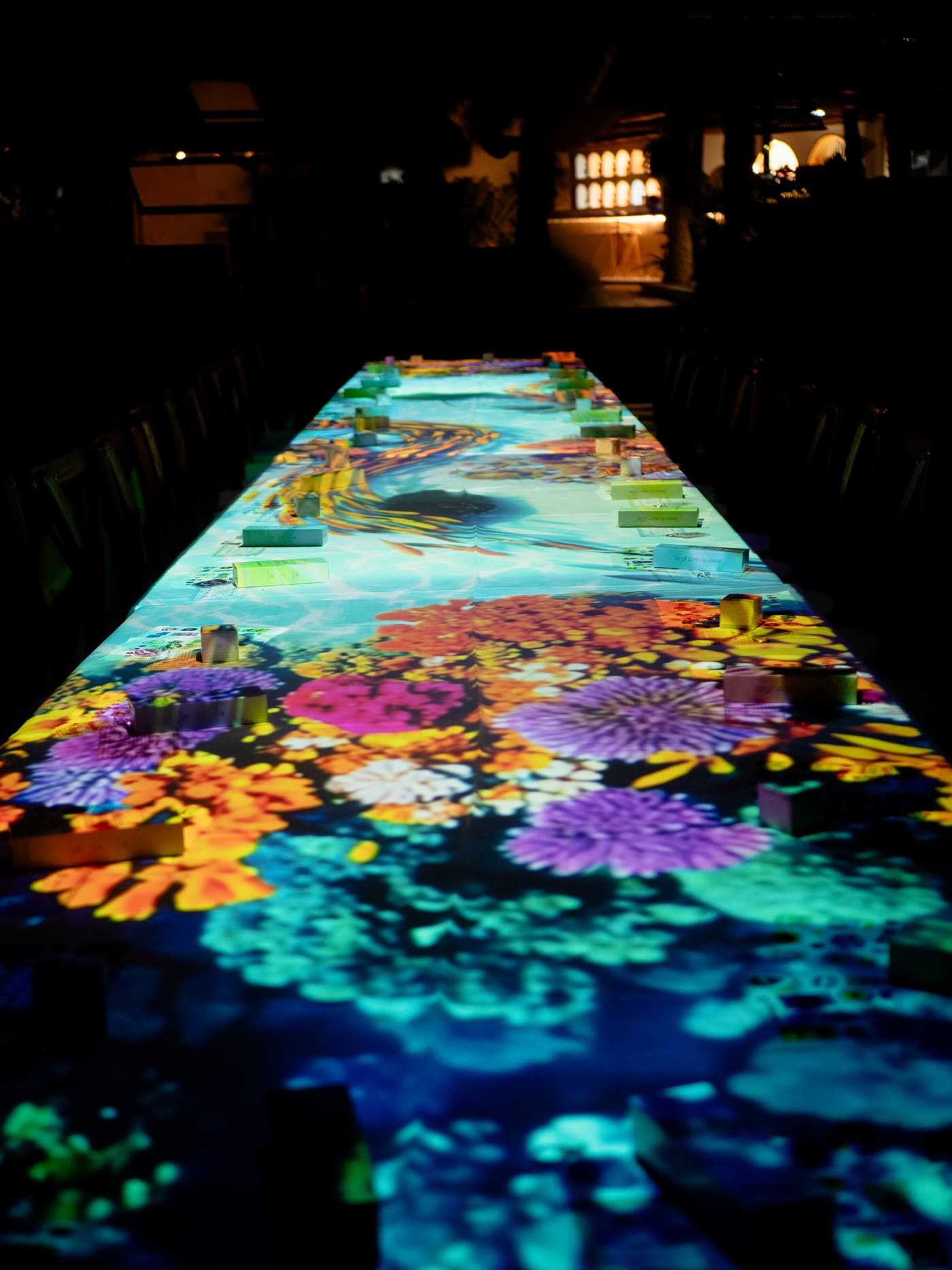 Mesa de 10 metros con videomapping de arrecife de coral durante una cena inmersiva en la playa